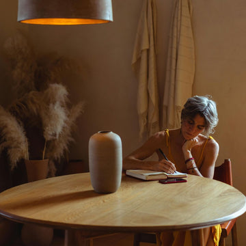Woman journaling at a table, illustrating daily journaling benefits for personal growth and mindfulness.